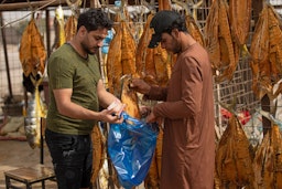 فروشنده‌ای در حال فروش ماهی خشک‌شده؛ شهر جنوبی بصره، عراق، ۹ اردیبهشت ۱۴۰۱/ ۲۹ آوریل ۲۰۲۲. (عکس از گتی ایمیجز)