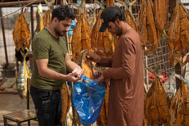فروشنده‌ای در حال فروش ماهی خشک‌شده؛ شهر جنوبی بصره، عراق، ۹ اردیبهشت ۱۴۰۱/ ۲۹ آوریل ۲۰۲۲. (عکس از گتی ایمیجز)