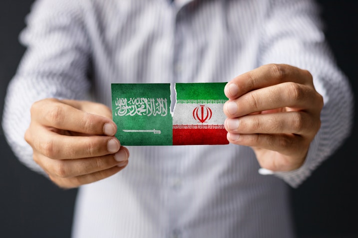 Close-up of a man holding the flags of Saudi Arabia and Iran. (Photo via Getty Images)