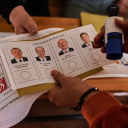 یک برگه‌‌ی رأی با چهره‌ی نامزدها در دستان یک مقام انتخاباتی؛ قرمان‌مرعش، ترکیه، ۲۴ اردیبهشت ۱۴۰۲/ ۱۴ می ۲۰۲۳. (عکس از گتی ایمیجز)