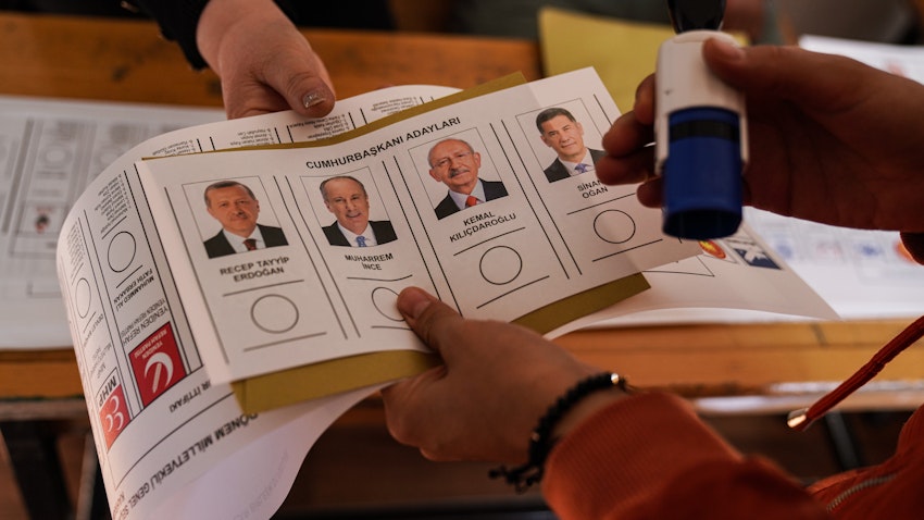 مسؤول انتخابي يعرض بطاقة اقتراع عليها وجوه المرشحين في كهرمانماراس، تركيا يوم 14 مايو/أيار 2023. (الصورة عبر غيتي إيماجز)