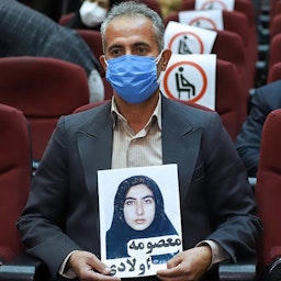 A victim's family member carries a photo during the in absentia trial of MEK members allegedly involved in killing civilians in the 1980s in Tehran, Iran on Mar. 7, 2021. (Photo via Mizan News Agency)