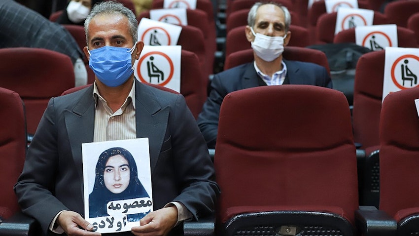 A victim's family member carries a photo during the in absentia trial of MEK members allegedly involved in killing civilians in the 1980s in Tehran, Iran on Mar. 7, 2021. (Photo via Mizan News Agency)
