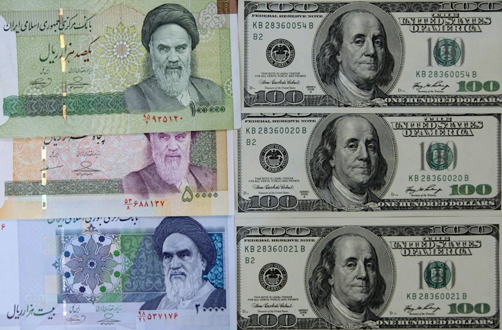 صورة لأوراق نقدية إيرانية متنوعة إلى جانب أوراق نقدية أميركية بقيمة 100 دولار. تم التقاط الصورة في طهران، إيران، في 18 يناير/كانون الثاني 2012. (الصورة عبر غيتي إيماجز)