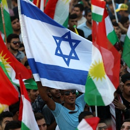أكراد عراقيون يلوحون بالأعلام الإسرائيلية والكردية خلال مناسبة في أربيل، شمال العراق. 16 سبتمبر/أيلول 2017. (الصورة عبر غيتي إيماجز)