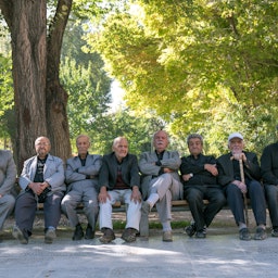 رجال إيرانيون كبار في السن يجلسون على مقاعد في حدائق جهل ستون في أصفهان، إيران، في 13 أكتوبر/تشرين الأول 2016. (الصورة عبر غيتي إيماجز)