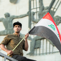 متظاهر يحمل العلم العراقي في ساحة التحرير ببغداد في 27 يوليو/تموز 2018. (تصوير مصطفى نادر عبر ويكيميديا كومنز)
