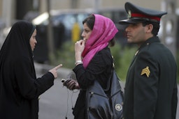 An Iranian woman is warned about her clothing and hair during a morality police crackdown to enforce the Islamic dress code, in Tehran, on Apr. 22, 2007. (Photo via Getty Images)