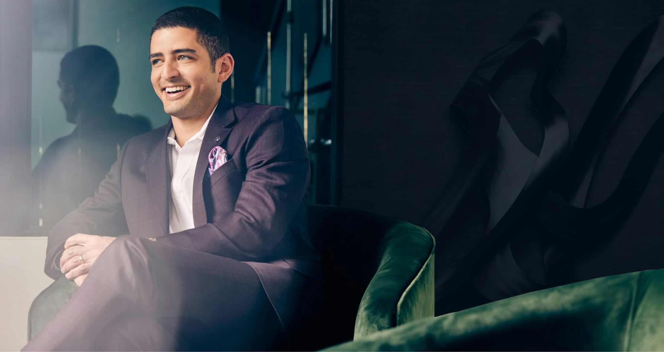 Banner image of Dr. Courtney sitting on a couch smiling in a purple suit