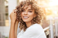 beautiful woman in white smiling with the sun shinning behind her