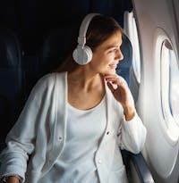 Brunette woman in white sitting on a plane looking out the window