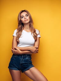 Gorgeous woman standing against a yellow wall.