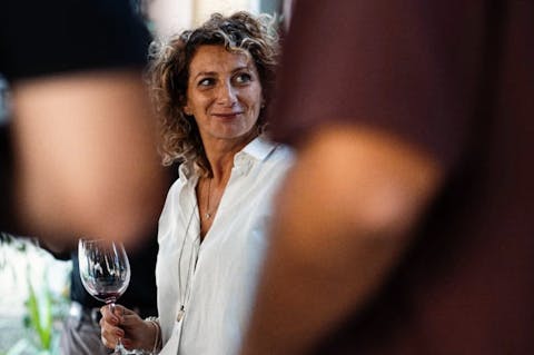 Claudia Piras, agente di commercio nel settore del vino, sorride mentre tiene in mano un calice di vino durante un’intervista.