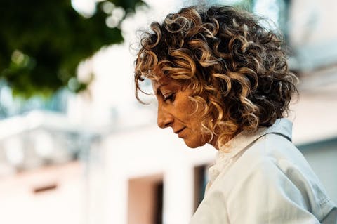 Ritratto di profilo di Claudia Piras, con lo sguardo rivolto verso il basso, in un ambiente all’aperto.