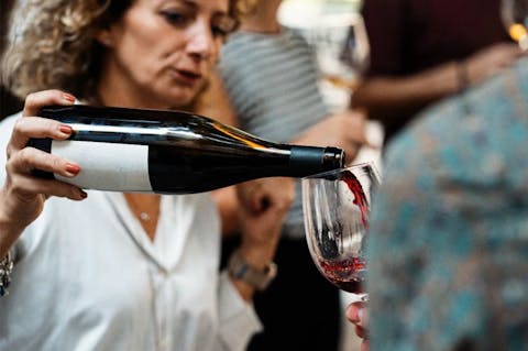 Claudia Piras versa il vino da una bottiglia in un calice, durante un momento di servizio.