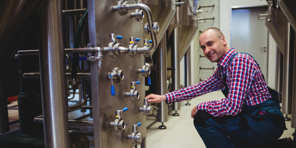 La trabajadora de una fábrica ajusta las válvulas de la máquina de agua caliente mientras se prepara para el siguiente paso en el proceso de elaboración de la cerveza.