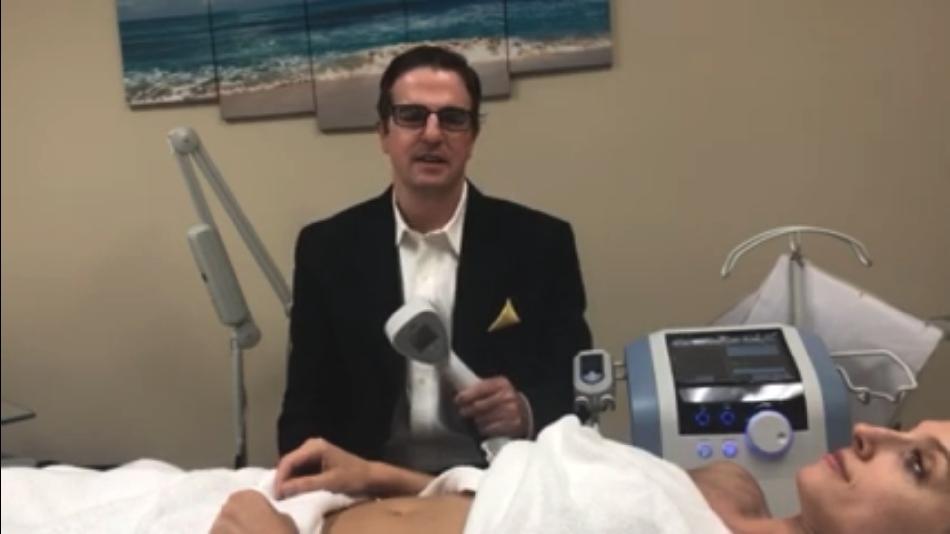 Dr. Wirth holding the Exilis device with a patient laying next to him