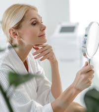 Female looking into a mirror examining her neck.