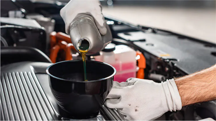 quick lube tech pouring oil into car engine