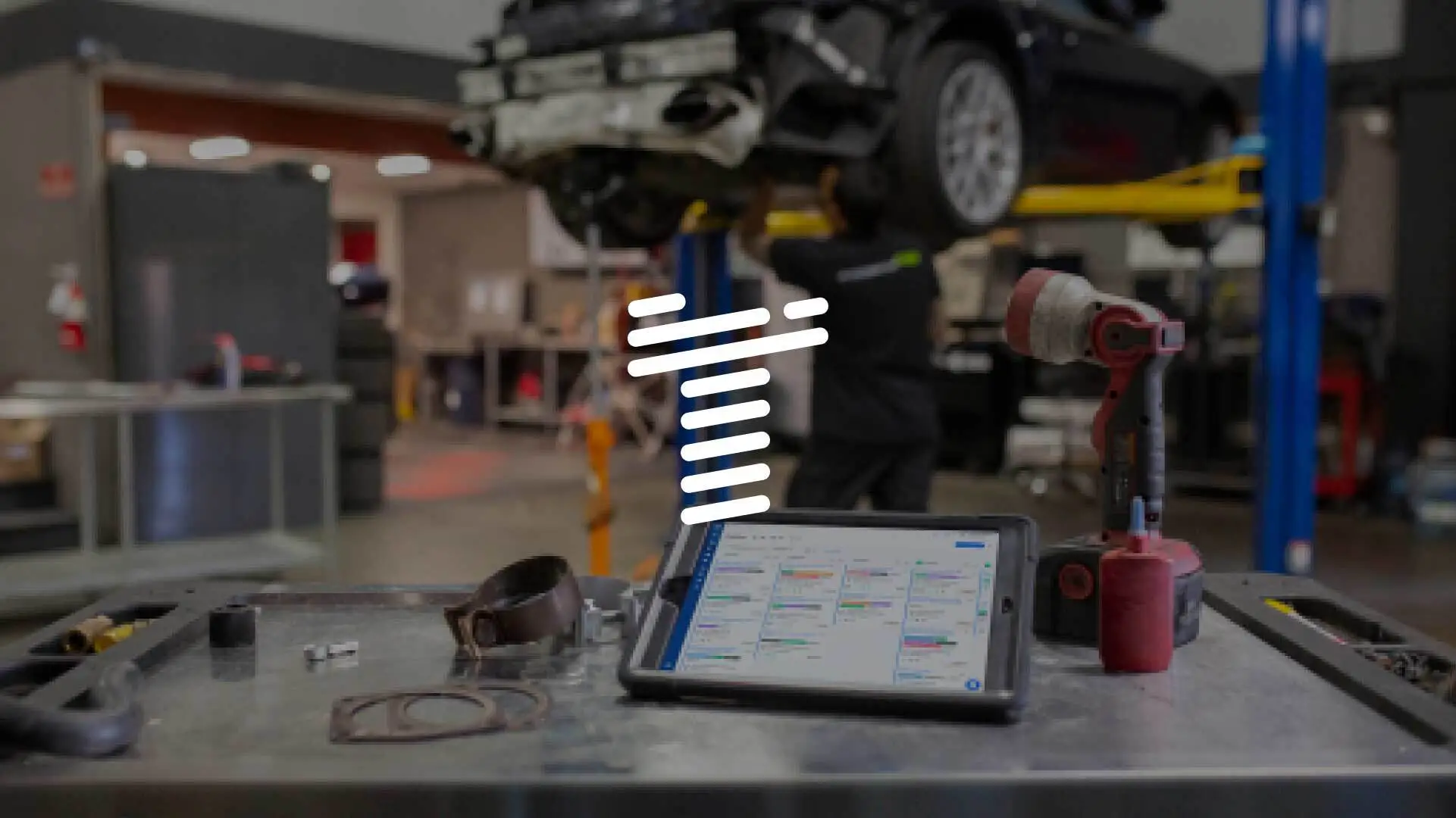 A stylized T over a background of an auto shop with an iPad using Shopmonkey.