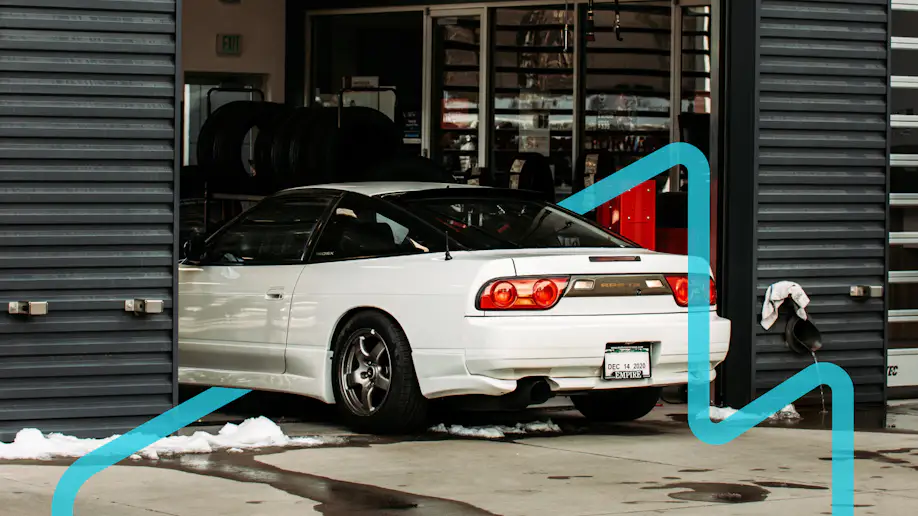 A white RPS 13 entering a shop in the winter with a blue graphic placed around it.