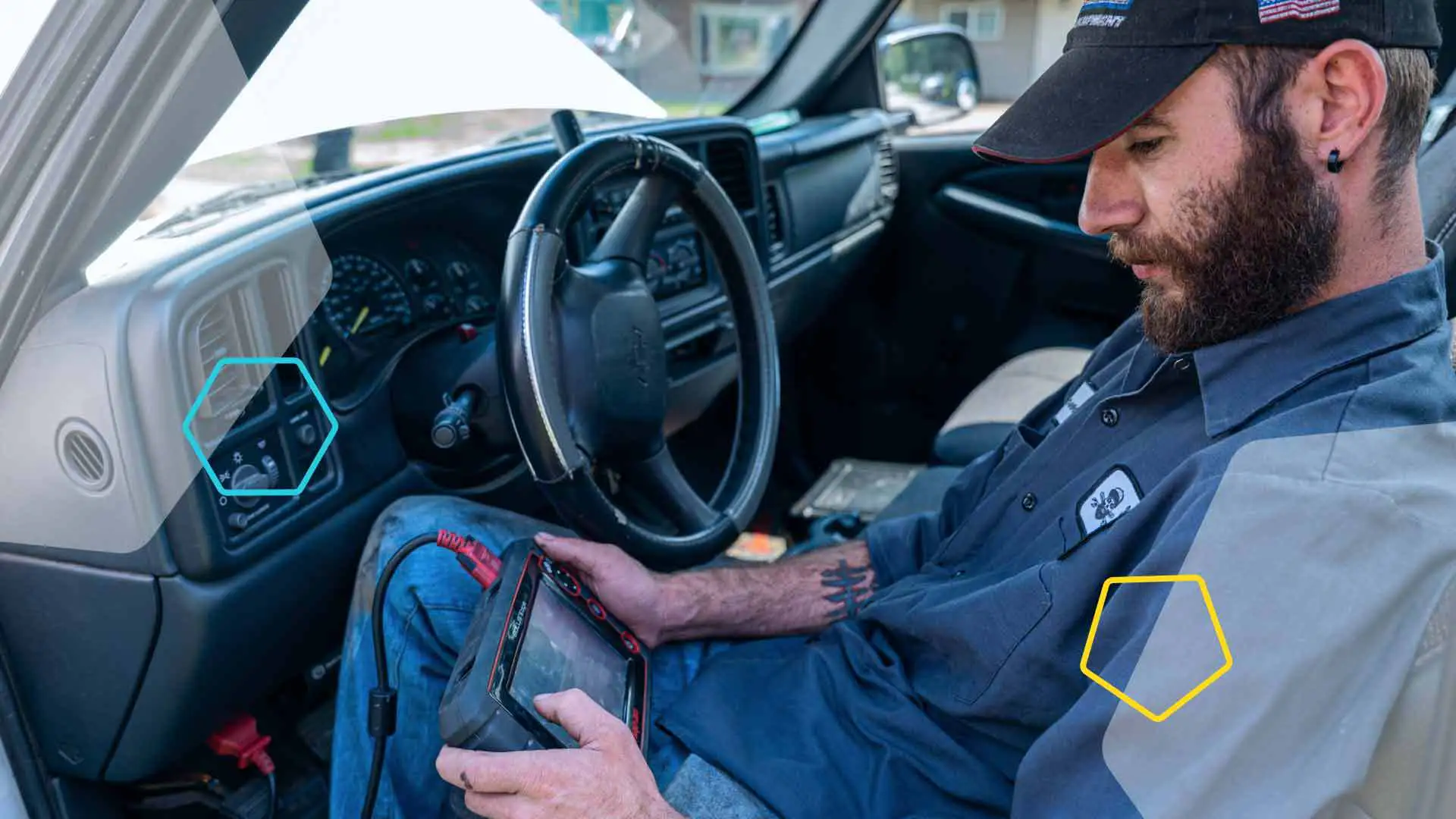 A bearded mobile mechanic running diagnostics while sitting in the drivers seat.