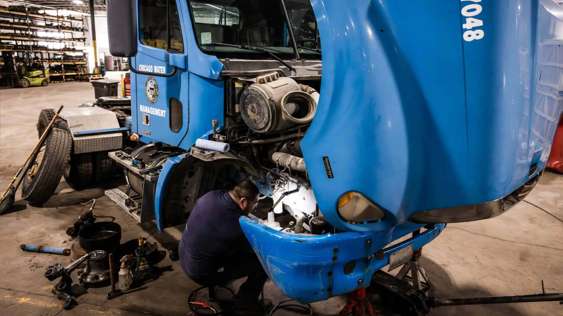 Man working on a blue semi truck in an HD shop