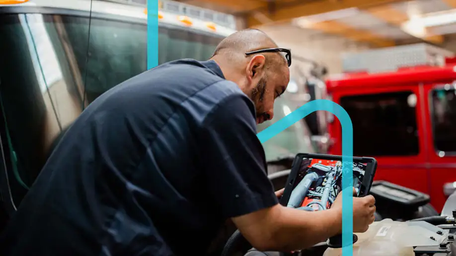 Man using Shopmonkey on a tablet in an auto shop with a blue graphic design.