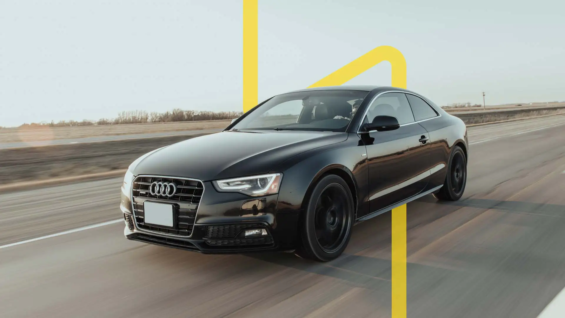 A black Audi driving on a road with a yellow line deign in the background.
