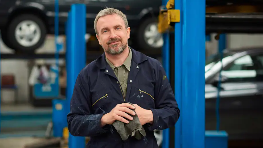 An auto shop owner wiping his hands with a rag.