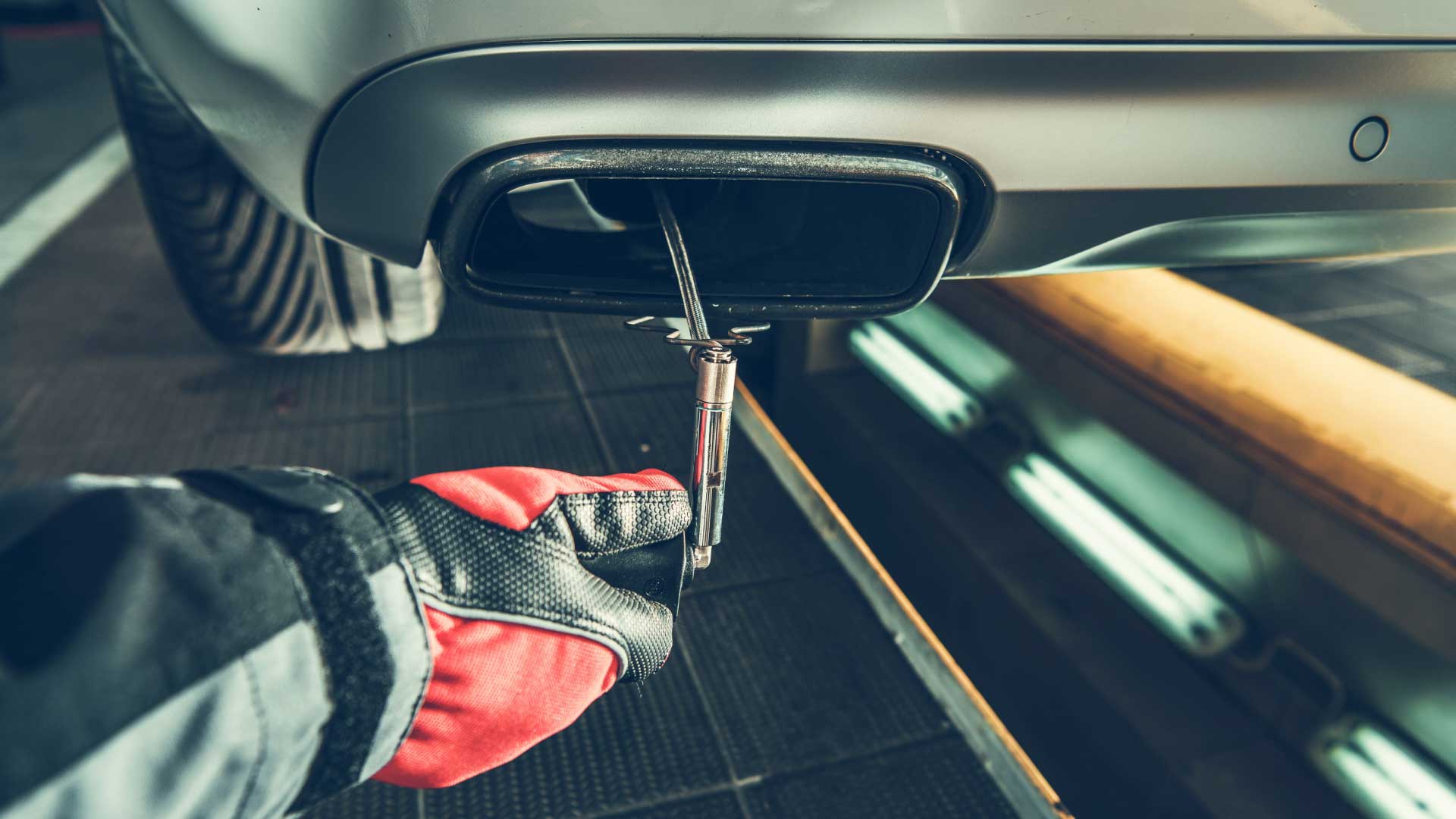 An auto repair technician conducting an emissions test on a vehicle.