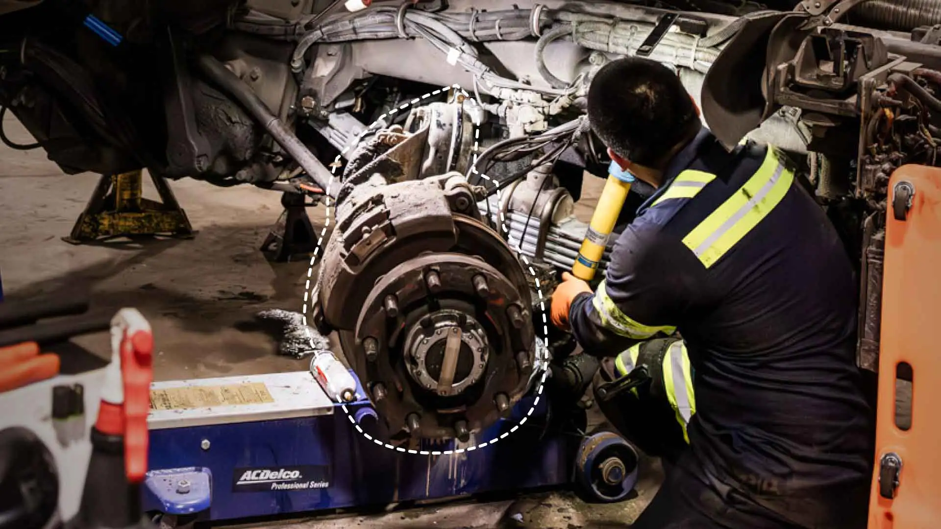 An auto technician working on a vehicle axle.