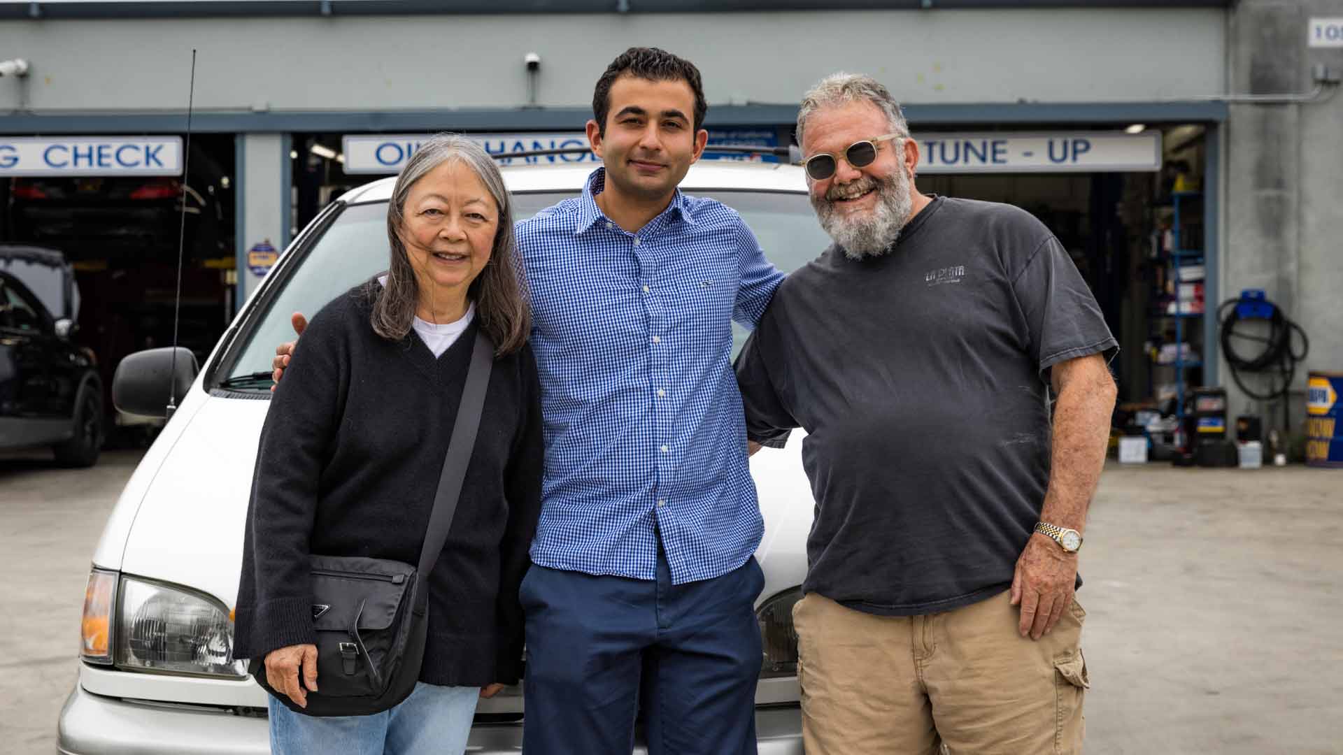 An auto repair shop owner alongside happy customers.