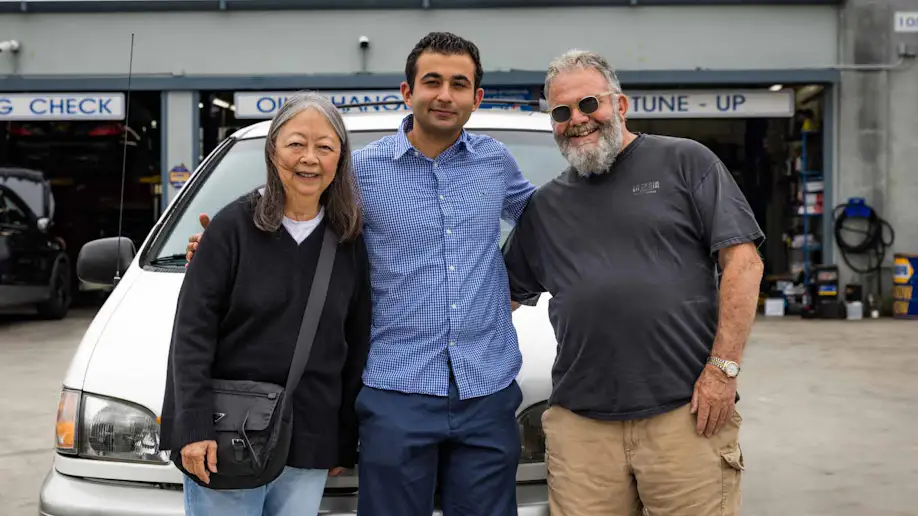 An auto repair shop owner alongside happy customers.