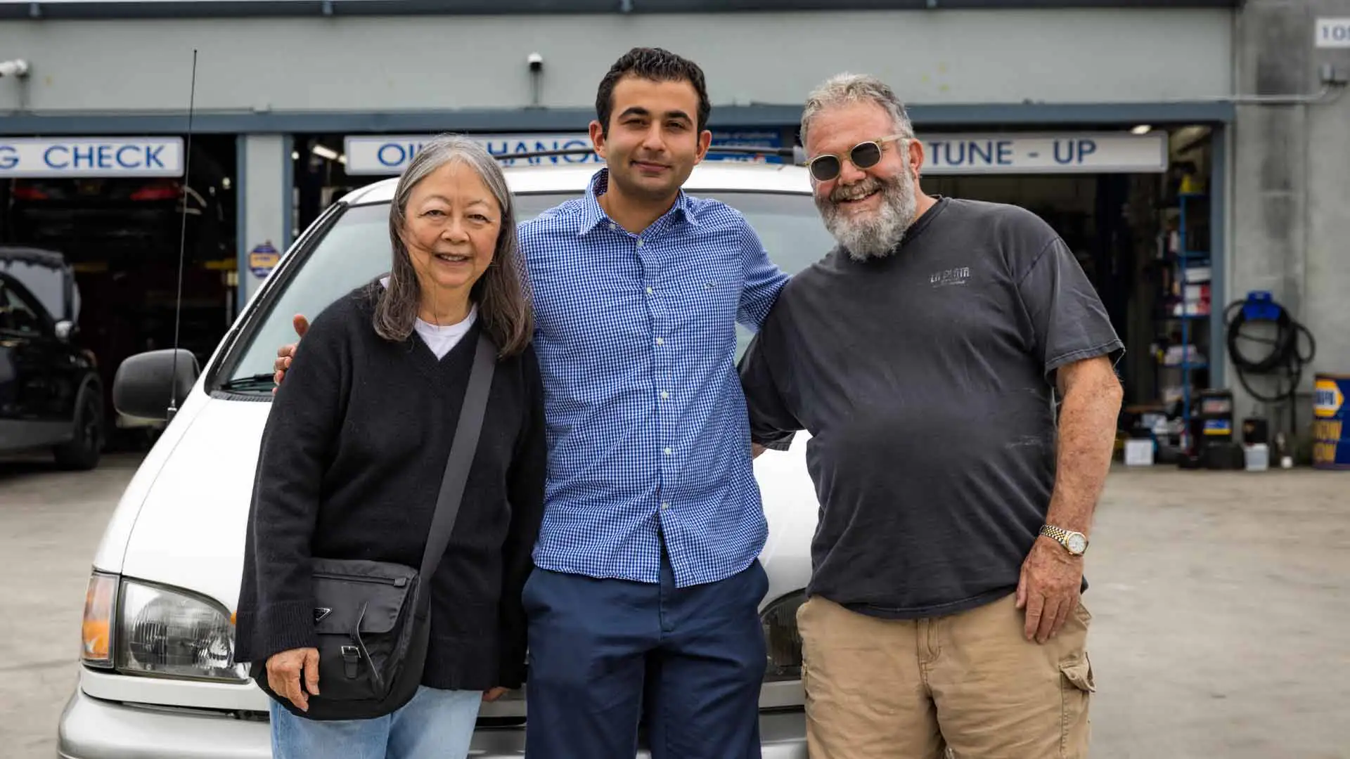 An auto repair shop owner alongside happy customers.