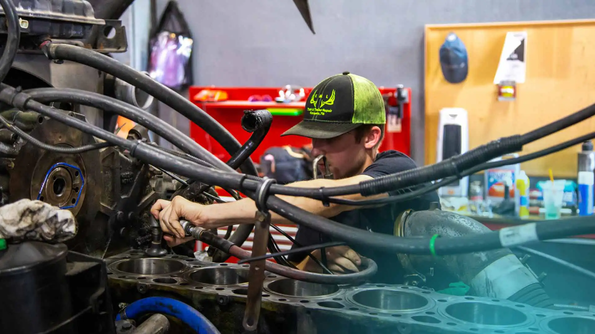 A truck repair shop technician working on a diesel engine.