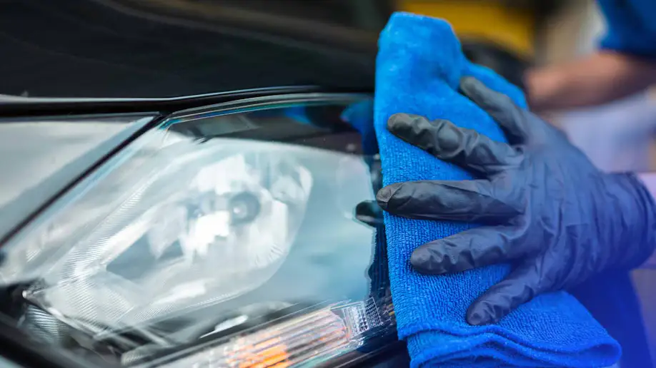 An auto detailer cleaning hazy headlights.
