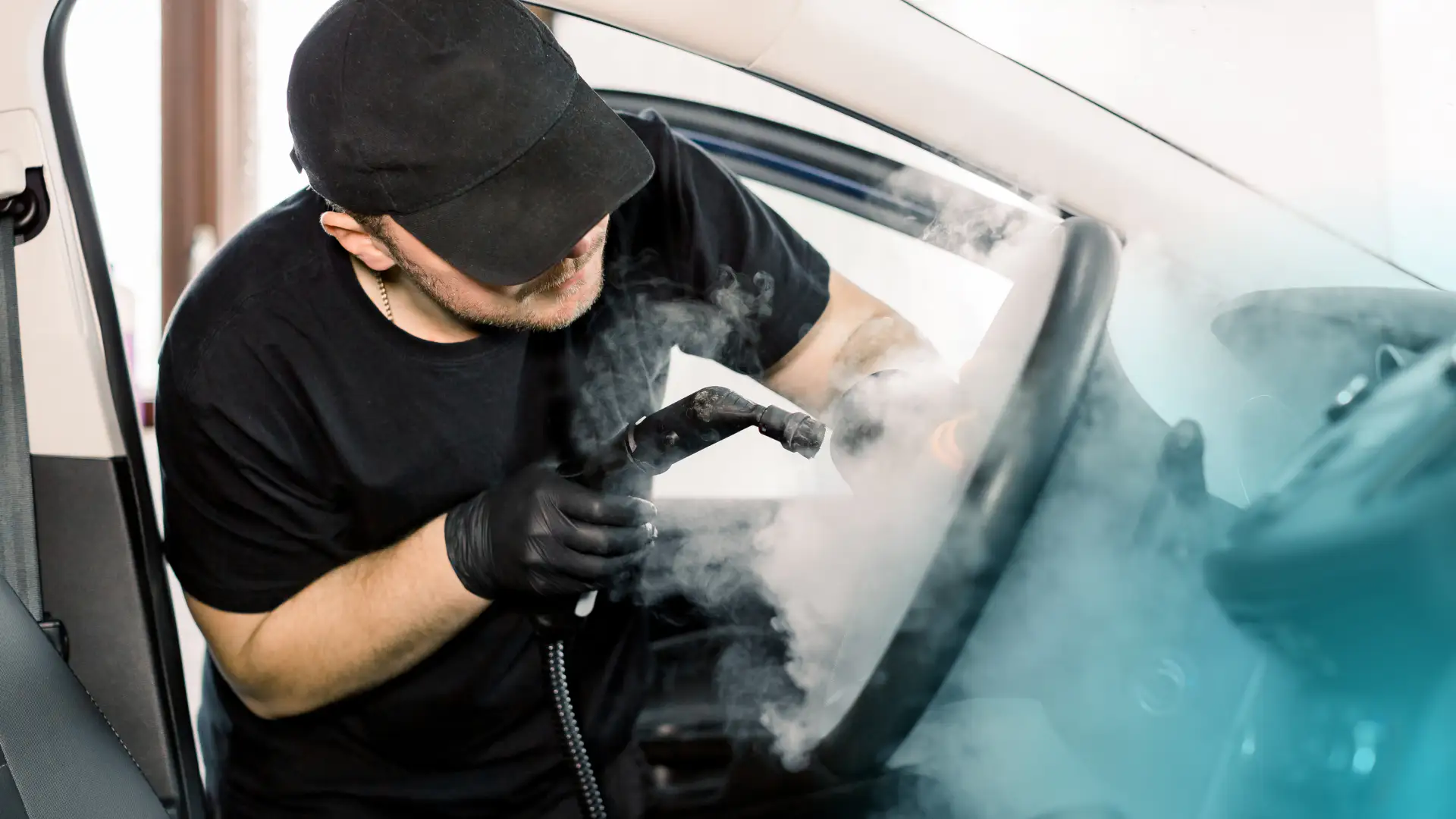 An auto detailer steam washing the interior of a vehicle.