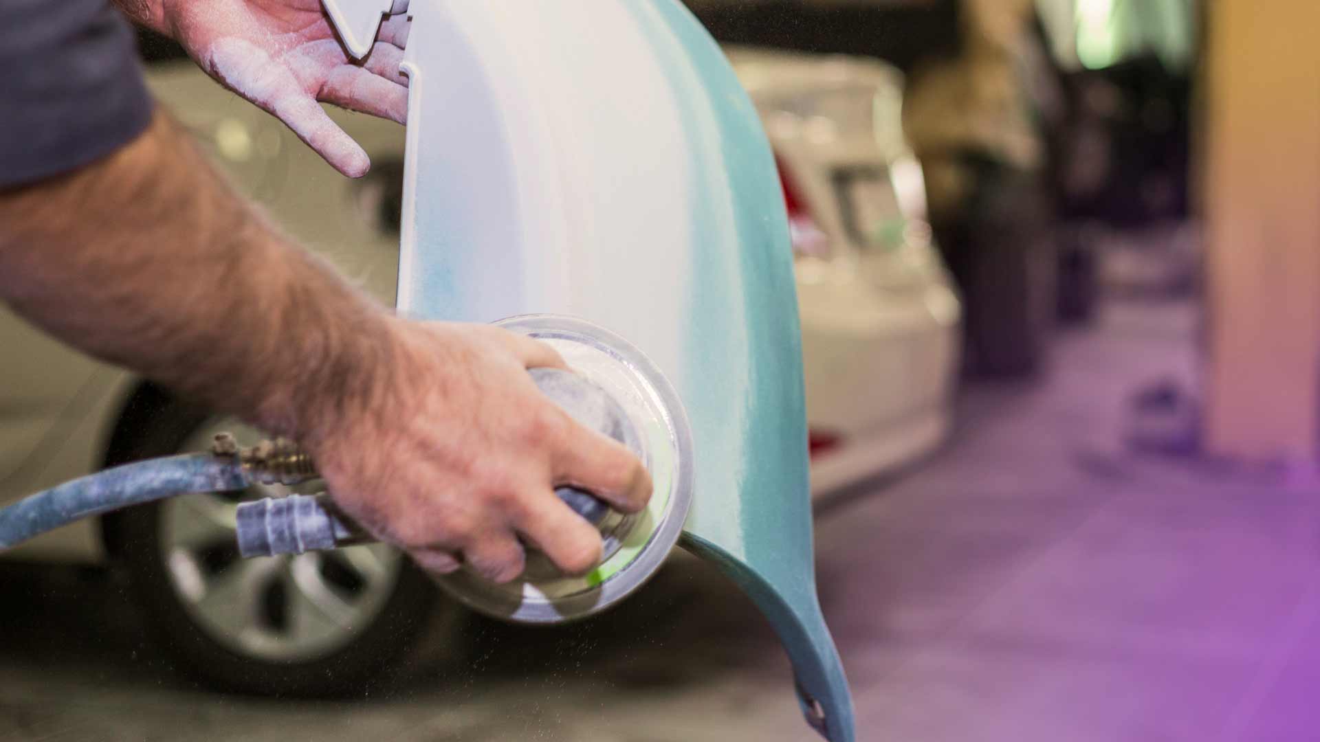 An auto technician repairing a scratched car bumper.