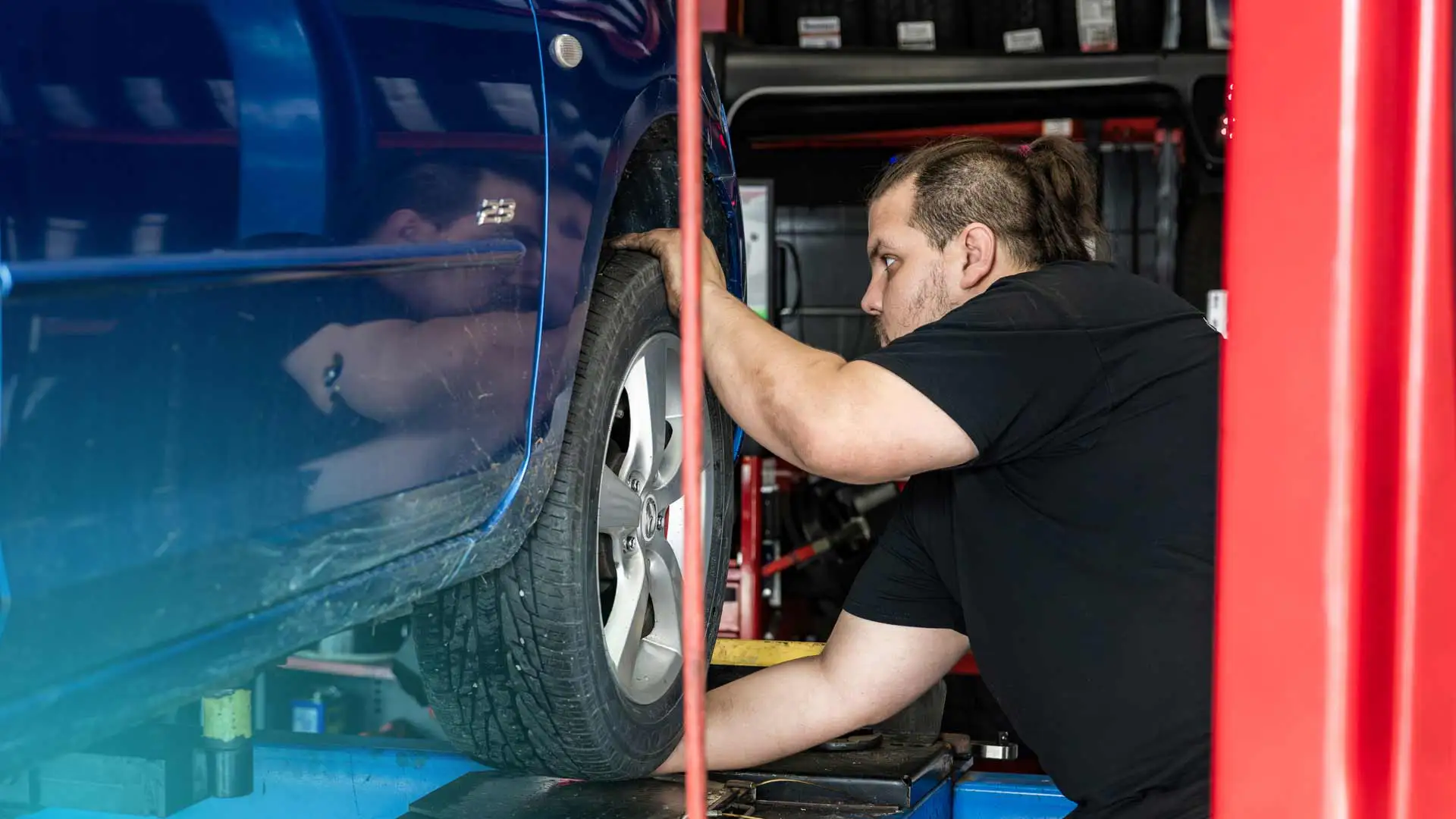 An auto repair technician replacing a tire rim.