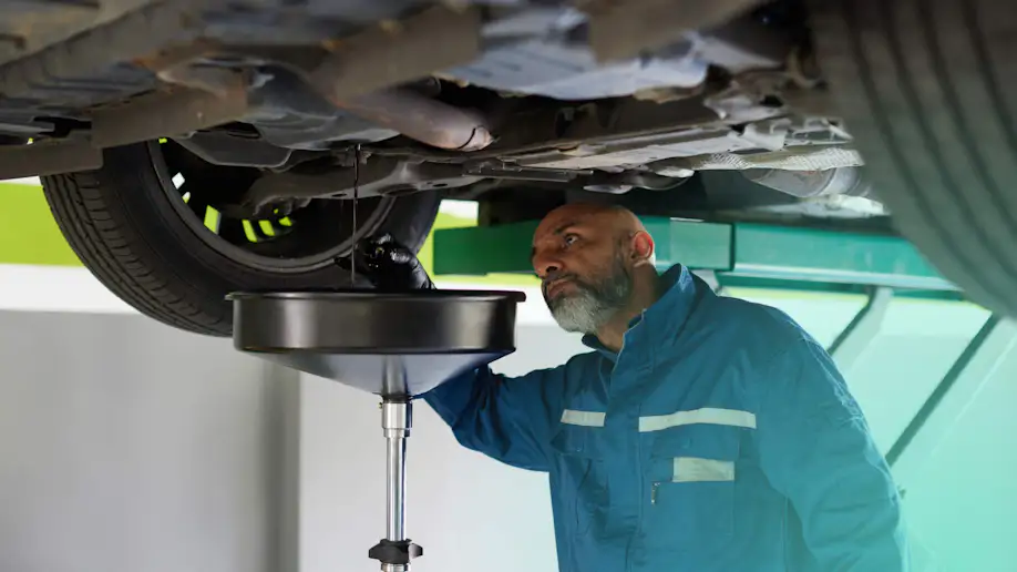 A quick lube technician doing an oil change for a customer.