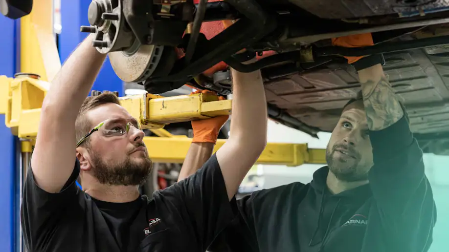 Two mechanics working on a vehicle.