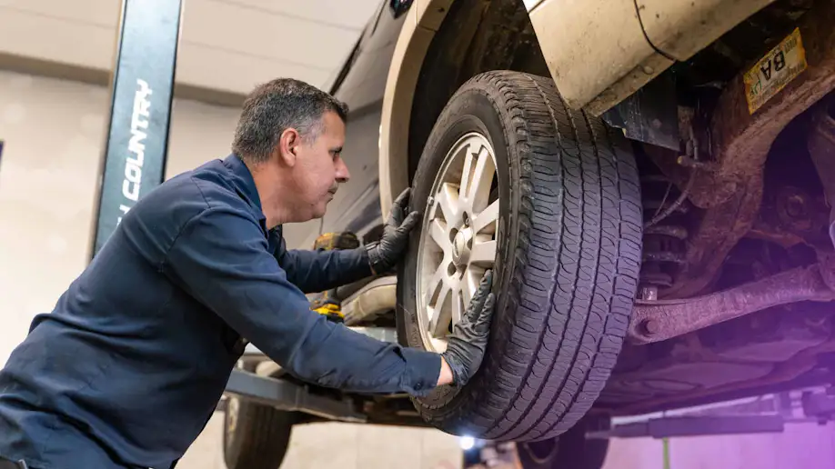 A tire shop technician inspecting a vehicle's tire.
