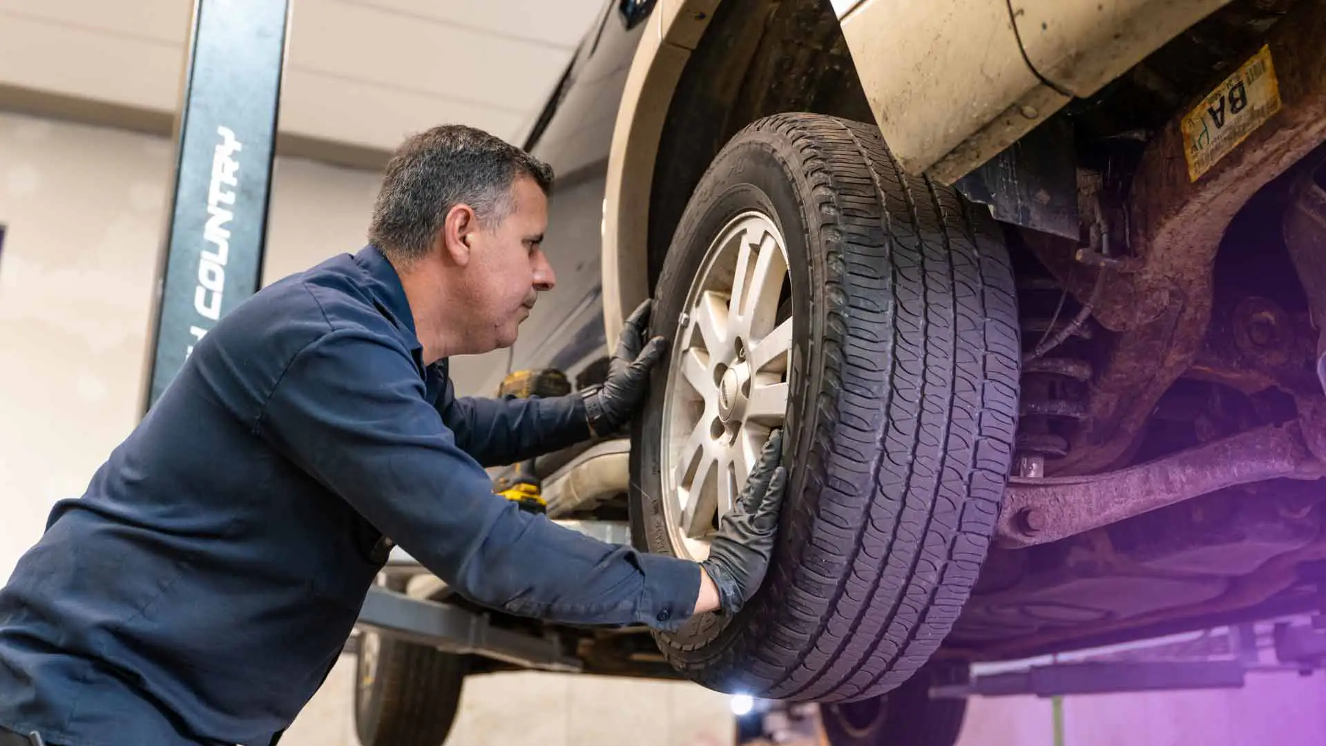 A tire shop technician inspecting a vehicle's tire.