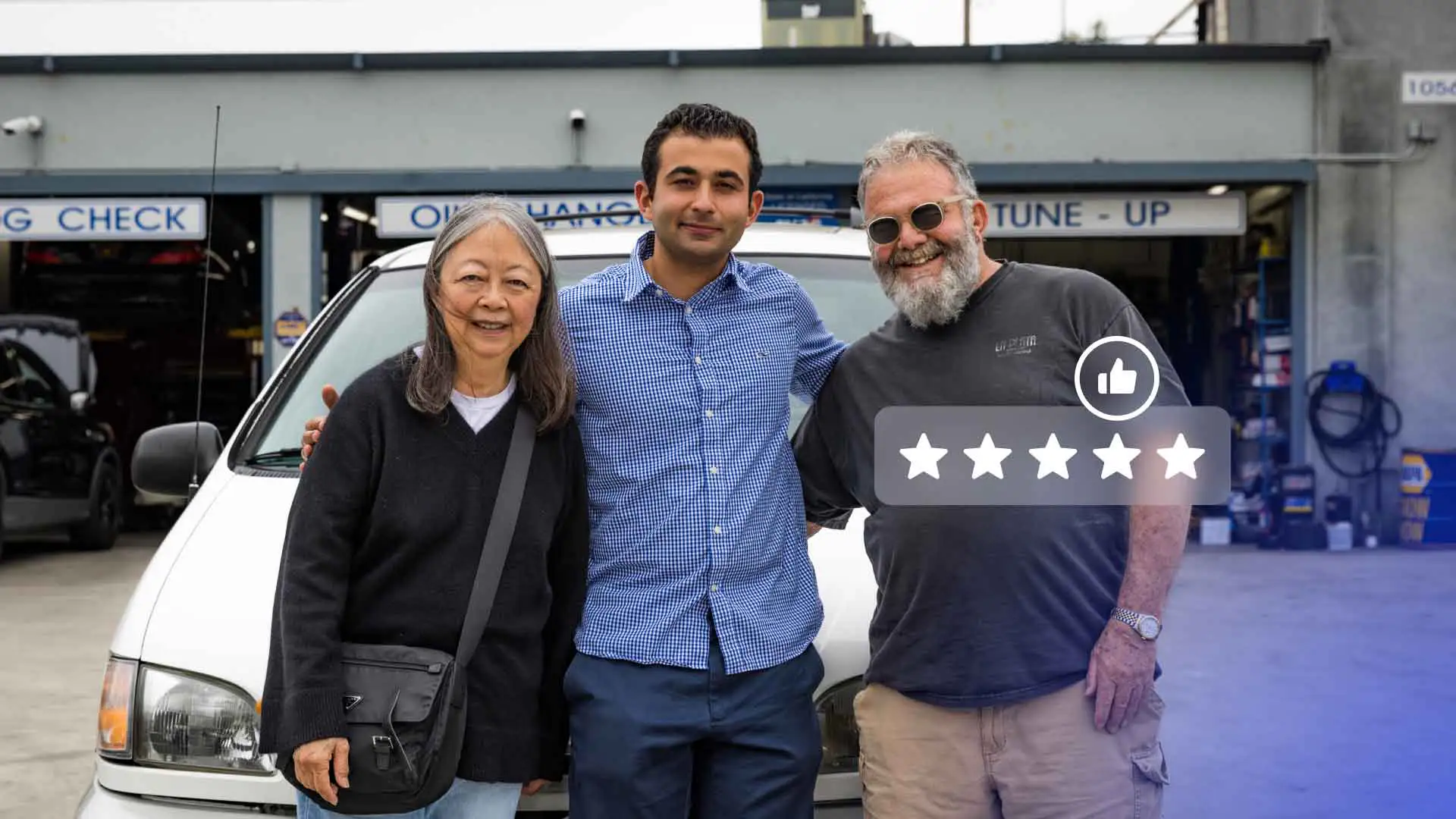 An auto repair shop owner standing with happy customers.