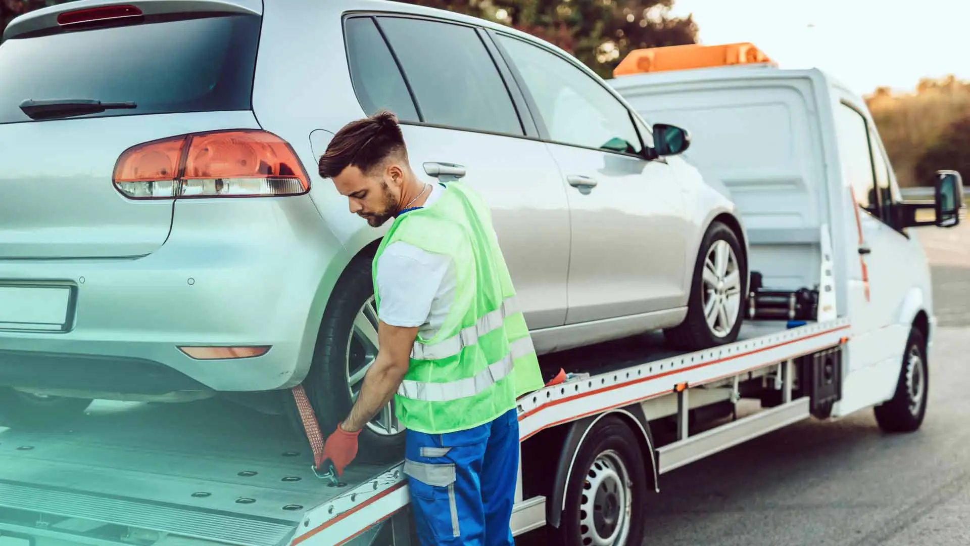 An auto technician towing a vehicle to their shop.