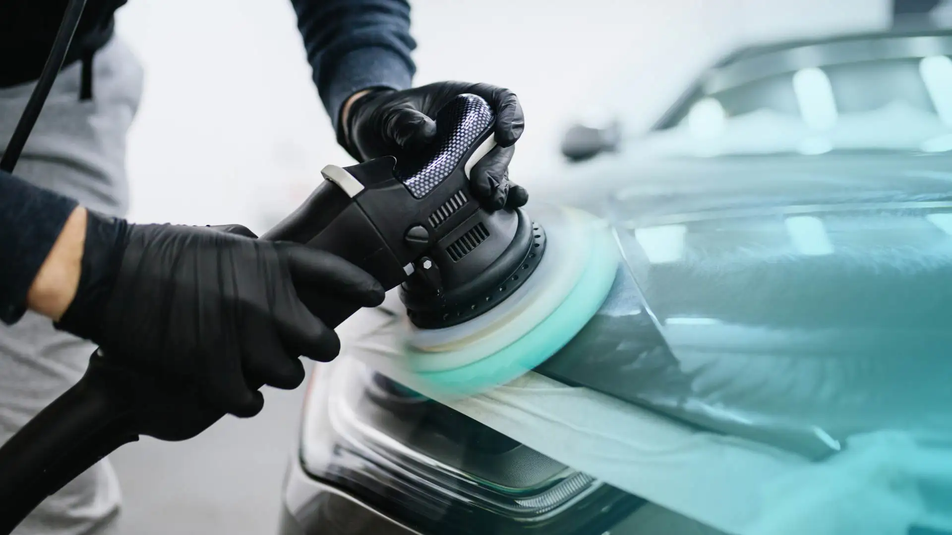 An auto detailer buffing a vehicle exterior.