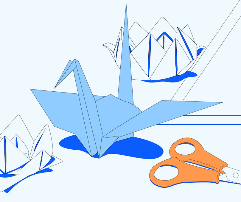 Two origami lotus flowers are next to an origami crane beside a set of scissors