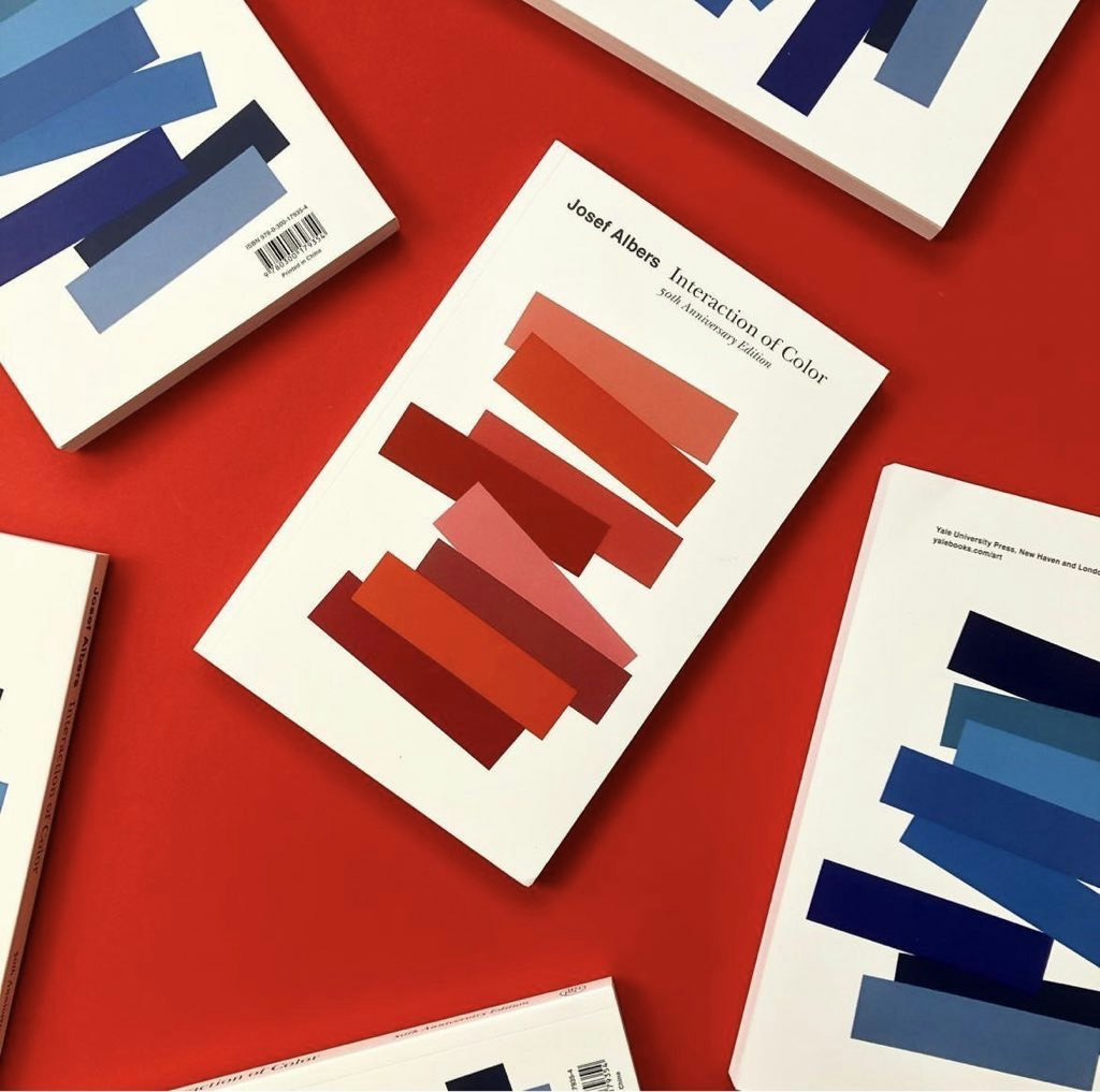 several books scattered over a red background, each book has red or blue stacked geometric shapes