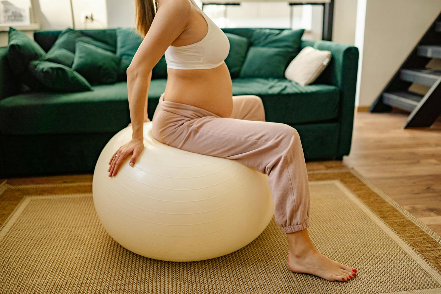 Pregnant woman sitting on a fitness ball in her living room